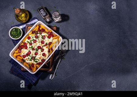 Patatine fritte caricate con la pizza. Pepperoni fatti in casa e formaggio Pizza French Fries. Patatine fritte al forno casseruola di patate con formaggio, peperoni salame e Foto Stock