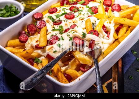 Patatine fritte caricate con la pizza. Pepperoni fatti in casa e formaggio Pizza French Fries. Patatine fritte al forno casseruola di patate con formaggio, peperoni salame e Foto Stock
