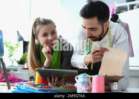 La donna di affari sta usando il tablet che comunica con lo stilista di moda Foto Stock