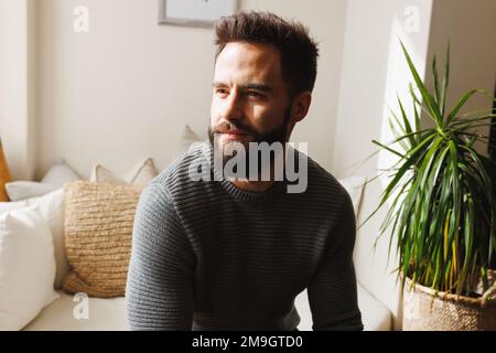 Giovane biraciale pensierato guardando lontano mentre si siede sul divano nel soggiorno, spazio copia Foto Stock