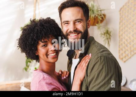 Primo piano ritratto di allegra coppia biraciale giovane abbraccio contro muro bianco, copia spazio Foto Stock