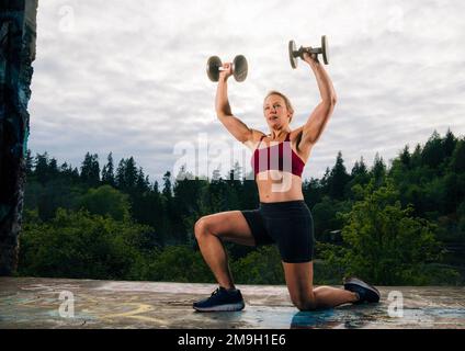 Donna che si esercita all'aperto con manubri, Bainbridge Island, Washington, USA Foto Stock