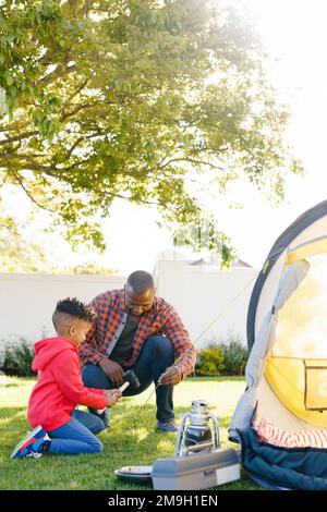 Felice afroamericano padre e figlio che pitching tenda nel loro cortile Foto Stock