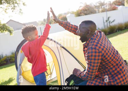 Felice afroamericano padre e figlio alto-fiving nel loro cortile Foto Stock