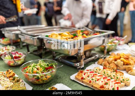 Vassoio di riscaldamento con cibo e persone sullo sfondo. Pranzo o cena a base di festa. Foto Stock