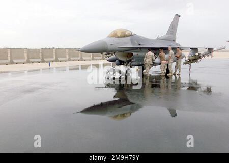 020104-F-3356N-007. [Complete] Scene Caption: Crewchiefs in attesa di un F-16C Fighting Falcon caricato, 354th Fighter Wing, 18th Fighter Squadron, Eielson AFB, Alaska, Siede sulla rampa bagnata dalla pioggia in una posizione operativa in avanti nel sud-ovest asiatico a sostegno di un'operazione CHE PERDURERÀ LA LIBERTÀ. La F-16C è dotata di due missili aria-aria AIM-120A Advanced Medium Range (AMRAAM), due AIM-9 Sidewinder e quattro bombe GBU-12 Paveway II da 500 libbre. È inoltre dotato di un sistema Martin Marietta Low-Altitude Navigation and Targeting Infrared for Night (LANTIRN). La F-16C è un aereo da combattimento compatto e multirole. Foto Stock