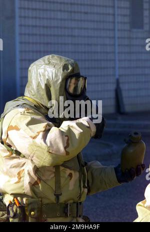 A Marine with Combined Joint Task Force (CJTF) si prepara a prendere un drink dalla sua mensa in Mission-Oriented Protective Posture Response Level 4 (MOPP-4) Gear durante un allenamento di allenamento Camp Doha, Kuwait durante IL FUNZIONAMENTO CHE PERCORRE LA LIBERTÀ. Il Marine è vestito con la sua Joint Service Lightweight Integrated Suit Technology (JSLIST), indossando una maschera di campo chimico-biologico M40 con filtro C2A1. Subject Operation/Series: ENDURING FREEDOM base: Camp Doha Paese: Kuwait (KWT) Scene Major Command mostrato: CJTF Foto Stock