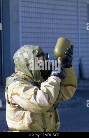 In attrezzatura di livello 4 (MOPP-4) con risposta posturale protettiva orientata verso la missione. Un Marine, vestito con la sua Joint Service Lightweight Integrated Suit Technology (JSLIST), indossando una maschera di campo chimico-biologico M40 con filtro C2A1, e cappuccio di protezione del campo, con la Combined Joint Task Force (CJTF) prende una bevanda dalla sua mensa durante un corso di allenamento di Doha, Kuwait durante il funzionamento CHE DURA LA LIBERTÀ. Subject Operation/Series: ENDURING FREEDOM base: Camp Doha Paese: Kuwait (KWT) Scene Major Command mostrato: CJTF Foto Stock