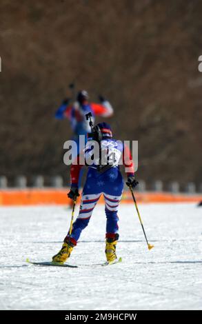 Con il suo fucile bolt-action, calibro .22, sbattuto sulla schiena, World Class Athlete Sergeant (SGT) Kristina Sabasteanski, USA, si alza in salita per gli ultimi metri dell'evento femminile di biathlon 15km tenutosi a Soldier Hollow a Midway, Utah, durante i GIOCHI OLIMPICI INVERNALI del 2002. Sullo sfondo, un membro del team la invita a proseguire. SGT Sabasteanski ha concluso una deludente 55th su 69 concorrenti con un tempo di 55:00,9. Soggetto operativo/Serie: Giochi OLIMPICI INVERNALI 2002 base: Midway Stato: Utah (UT) Paese: Stati Uniti d'America (USA) Foto Stock