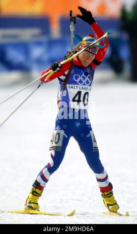 SPECIALISTA della Guardia Nazionale (SPC) Kara Salmela, USA, raggiunge per il suo fucile da bolt-action calibro .22 come lei entra nella parte di tiro della gara di 7,5km Biathlon Sprint femminile a Solider Hollow durante i GIOCHI OLIMPICI INVERNALI 2002. SPC Salmela finirebbe la gara 59th assoluta, 57:25,9 alle spalle del leader. Soggetto operativo/Serie: Giochi OLIMPICI INVERNALI 2002 base: Midway Stato: Utah (UT) Paese: Stati Uniti d'America (USA) Foto Stock