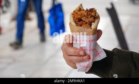 Uomo che tiene e mangia Gyro fuori. Fast food greco tradizionale. Foto Stock