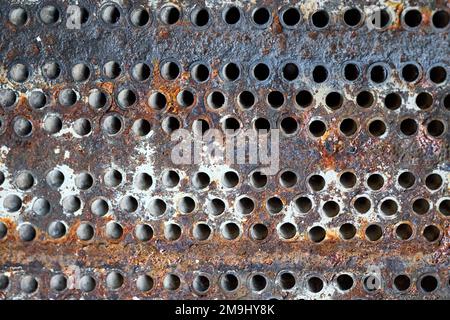 Piastra tubiera in lamiera di scambiatore di calore o di boiler closeup texture macro fondo industriale con insolubile depositi minerali duri saldatura a scala di sali Foto Stock