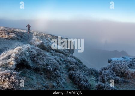 Rompere la nebbia su Ilkley Moor in una giornata fredda con il gelo denso sull'erica. Un corridore è caduto in esecuzione su Ilkley Moor con la luna in alto dentro Foto Stock