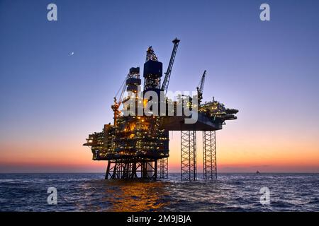 Piattaforma offshore per il petrolio e il gas nel mare al tramonto. La produzione di petrolio greggio nell'oceano. Foto Stock