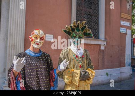 Artisti di strada veneziani mascherati vestiti in costumi da carnevale che si esibiscono per turisti a Venezia. Foto Stock