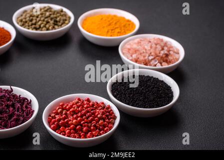 Composizione costituita da una variazione di diversi tipi di spezie in ciotole di ceramica bianca su fondo in cemento Foto Stock