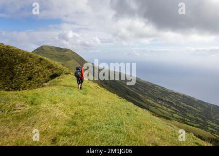 Persona escursionismo lungo un vecchio bordo del cratere vulcanico sull'isola di São Jorge nelle Azzorre Foto Stock