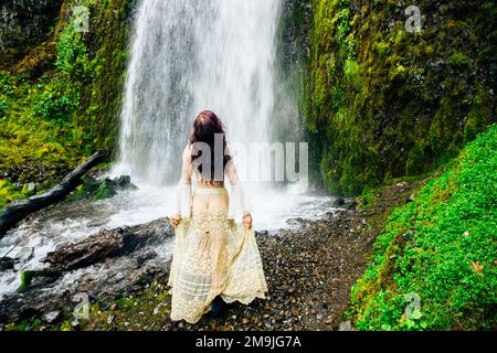 Donna in piedi di fronte alla cascata, Multnomah Falls, Columbia River Gorge, Oregon, USA Foto Stock