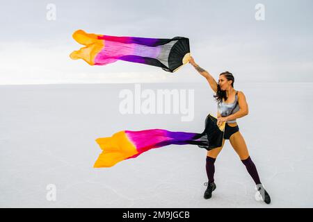 Giovane donna ginnica con bandiere vicino al lago, Bonneville Salt Flats, Utah, USA Foto Stock