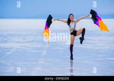 Giovane donna ginnica con bandiere vicino al lago, Bonneville Salt Flats, Utah, USA Foto Stock