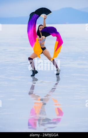 Giovane donna ginnica con bandiere vicino al lago, Bonneville Salt Flats, Utah, USA Foto Stock