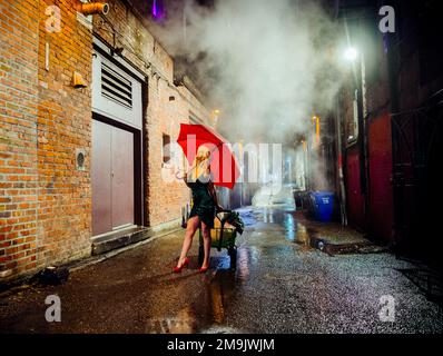 Donna con ombrello rosso in vicolo di notte, Seattle, Washington, USA Foto Stock