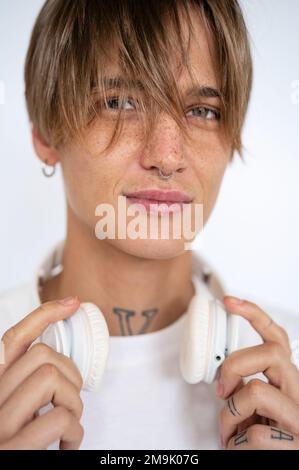 Ritratto elegante bionda a capelli corti giovane donna con i tatuaggi di reckles che piercing sul viso e corpo tenendo le cuffie sul collo. Foto Stock