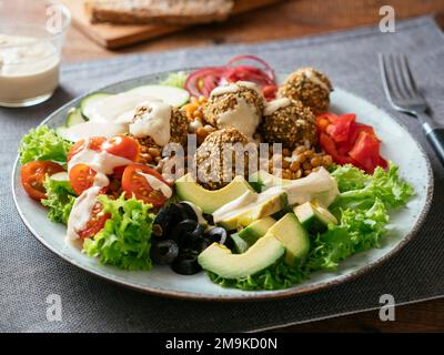 Insalata mista sana come cena con palline di falafel fatte in casa e un condimento di tahini. Foto Stock