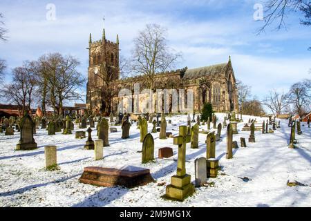 Il cimitero innevato e le lapidi nella parrocchia di Santa Maria chiesa Sandbach Cheshire Inghilterra in inverno Foto Stock