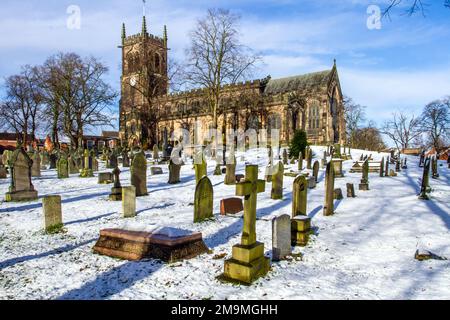 Il cimitero innevato e le lapidi nella parrocchia di Santa Maria chiesa Sandbach Cheshire Inghilterra in inverno Foto Stock