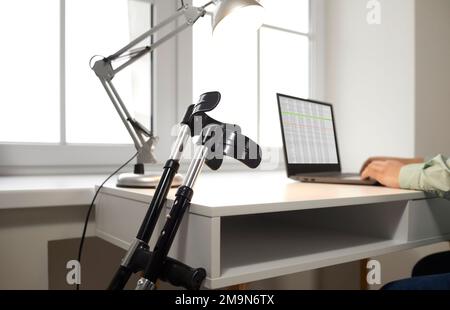 Stampelle in primo piano sullo sfondo del luogo di lavoro con il computer portatile durante il lavoro remoto. Foto Stock