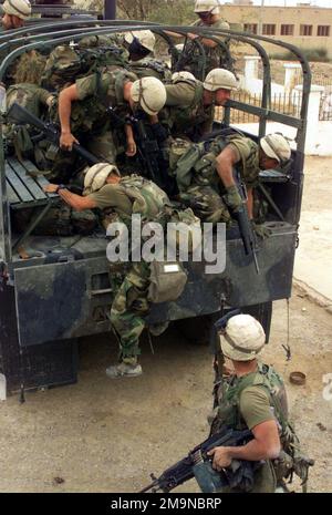 Marines di Echo Company, Battalion Landing Team (BLT), 2nd Battalion, 2nd Marines, 24th Marine Expeditionary Unit (Special Operations Capable) (MEU SOC) salta fuori da un Medium Tactical Vehicle Replacement (MTVR) durante un raid nella sede centrale del Ba'th Party a Qalat Sukar, Iraq. I Marines sono dotati di fucili M16A2 da 5,56 mm e di una mitragliatrice Saco da 7,72 mm M60 per impieghi generali. Soggetto operativo/Serie: BASE PER LA LIBERTÀ IRACHENA: Qalat Sukar Stato: Dhi Qar Paese: Iraq (IRQ) Foto Stock