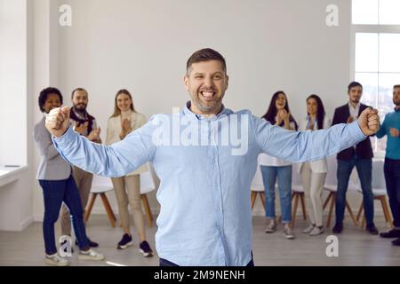 Felice divertente uomo d'affari fiducioso che celebra il suo successo con il team di dipendenti Foto Stock