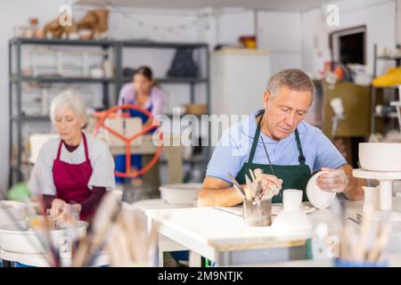 il vasaio dell'uomo dipinge con cura il vaso Foto Stock