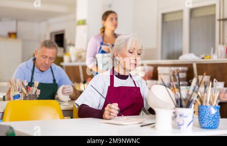 vasaio femmina dipinge vaso finito in bianco Foto Stock