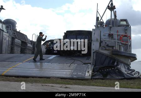 Un membro della Marina statunitense (USN) a bordo di un'imbarcazione USN Landing Craft, Air Samponed (LCAC) dirige un veicolo gommato multiuso ad alta mobilità (HMMWV) del corpo marino statunitense (USMC) sulla spiaggia all'interno del porto di Apra, Guam. La LCAC con la sua nave di supporto è qui per partecipare all'esercizio TANDEM SPINTA 2003. Base: US Naval Forces, Marianas Stato: Guam (GU) Nazione: Isole Marianne Settentrionali (MNP) Foto Stock