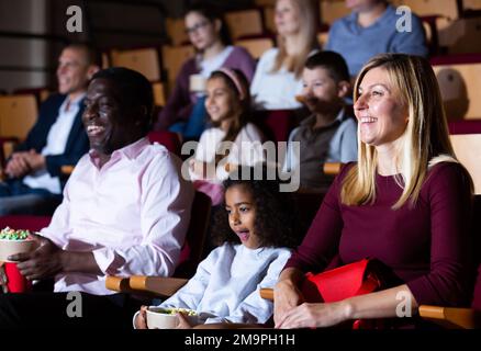 Donna ridente che guarda film divertente al cinema con la famiglia Foto Stock