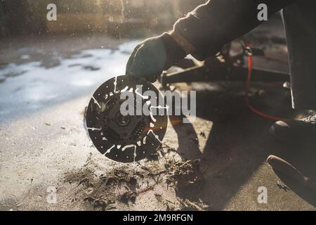 Mani di meccanico che tiene una vecchia frizione grigia argento rotta ad un negozio di riparazione auto. Foto di alta qualità Foto Stock