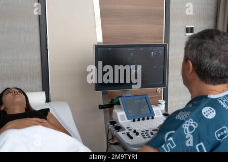 Medico che guarda le immagini ecografiche, medico che esamina ecografia di una paziente femminile e che parla con la donna della sua malattia Foto Stock