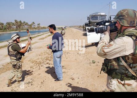 Durante la pattuglia pomeridiana lungo il perimetro del campo di Babilonia, i soldati polacchi tirano su una Volkswagen e mettono in discussione due civili iracheni. I due sono sospettati di avere armi illegali. US Air Force (USAF) STAFF Sergente (SSGT) Nathan Germann, videografo, Hill Air Force base (AFB), Utah (UT), documenta l'evento durante l'operazione IRACHENA LIBERTÀ. Soggetto operativo/Serie: BASE DELLA LIBERTÀ IRACHENA: Campo di Babilonia Paese: Iraq (IRQ) Foto Stock