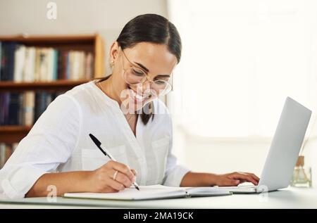Tenere traccia delle mie idee brillanti. una giovane donna d'affari che scrive nel suo diario mentre lavora da casa. Foto Stock
