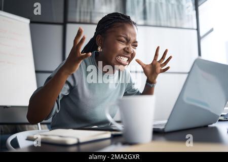 Le ceneri fumando ora. una giovane donna d'affari che guarda arrabbiata mentre usa un notebook in ufficio. Foto Stock