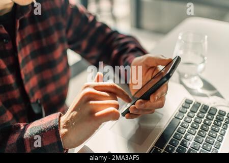 Giovane lavoratore studente d'affari che usa il telefono cellulare nelle mani, uomo che lavora online con lo smartphone. Foto Stock