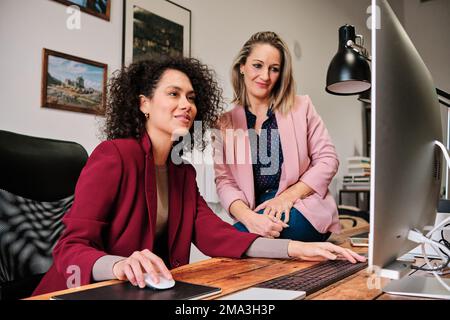 Colleghi che utilizzano il computer mentre lavorano insieme in ufficio. Foto Stock