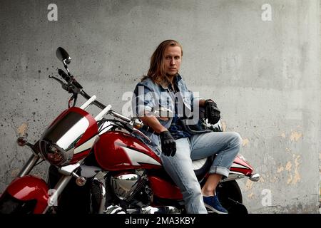 Un uomo in moto corre in un paesaggio urbano tra cemento, parcheggi, asfalto, stile di vita moto Foto Stock