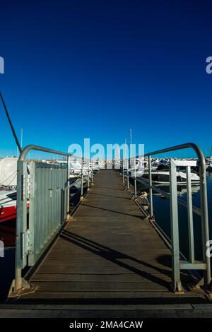 Passerella nel porto della città di Altea per raggiungere le barche che sono ormeggiate nelle sue acque sotto un bel cielo soleggiato. Foto Stock