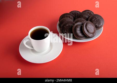 pasto fotografico biscotti con scaglie di cioccolato su un piatto con una tazza di caffè caldo su un piattino Foto Stock