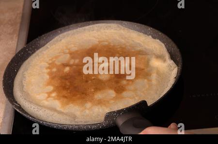 foto della pastella per frittelle sottili fritte in padella su una stufa da cucina Foto Stock