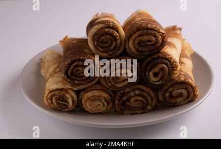 foto frittelle sottili giacenti su un piatto su uno sfondo bianco Foto Stock