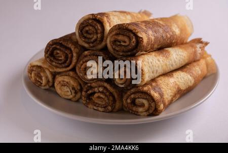 foto di deliziose frittelle fritte sdraiate su un piatto intrecciato in tubi su sfondo bianco Foto Stock